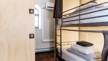 A bunk bed room with a window, a door with a number, and a radiator.