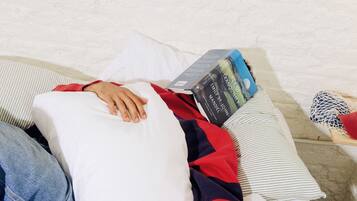 A person lying on a bed with a book and a pillow.