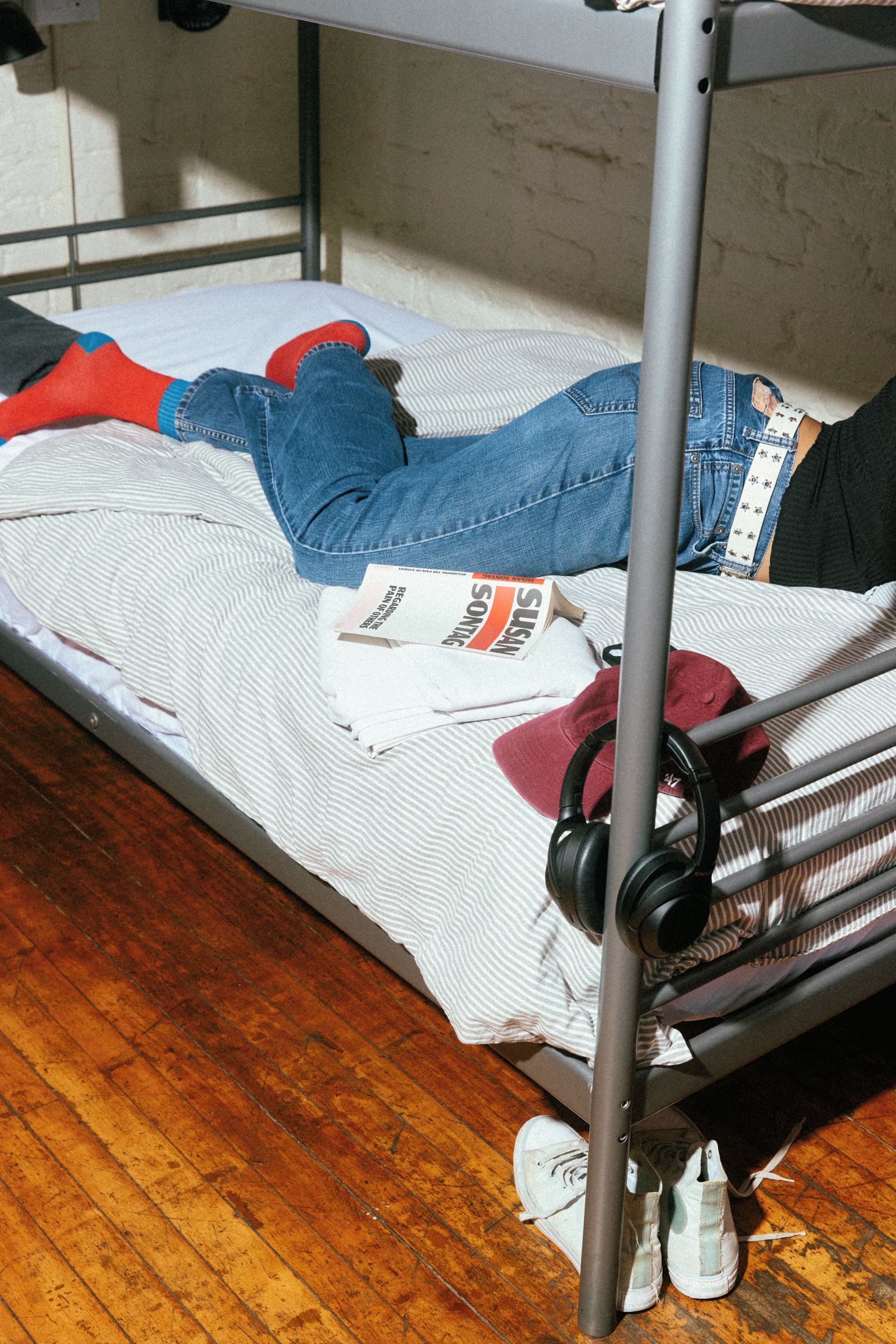 A bed with a metal frame, a striped blanket, and a pair of jeans.