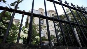 A building with a sign reading "Ottawa International Hostel" behind a metal fence with birds perched on it. - Saintlo Ottawa Jail Hostel (Ottawa)