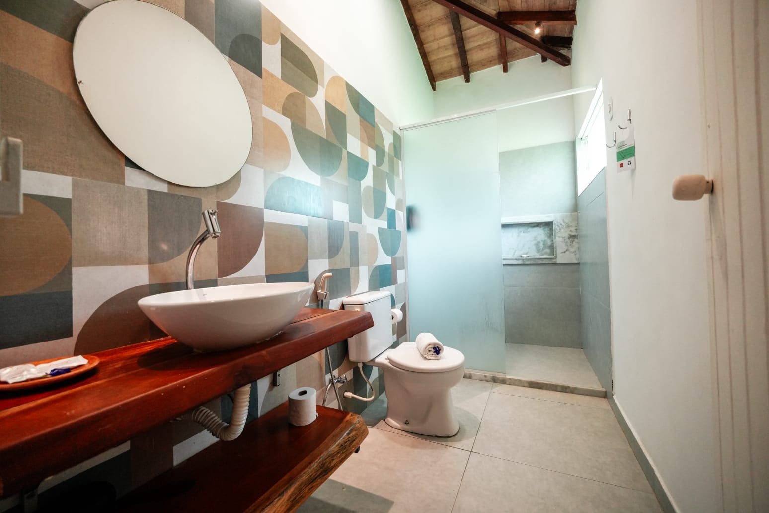 A bathroom with a large white sink, a toilet, and a shower area.