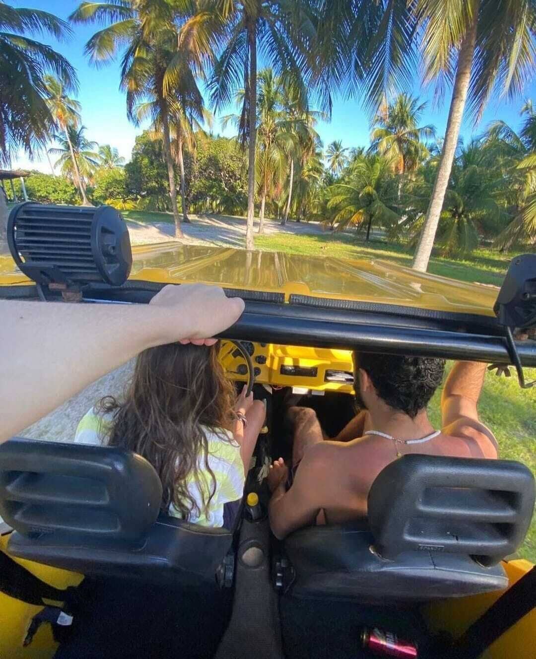 Un véhicule jaune avec deux passagers, dont l’un tient le volant.