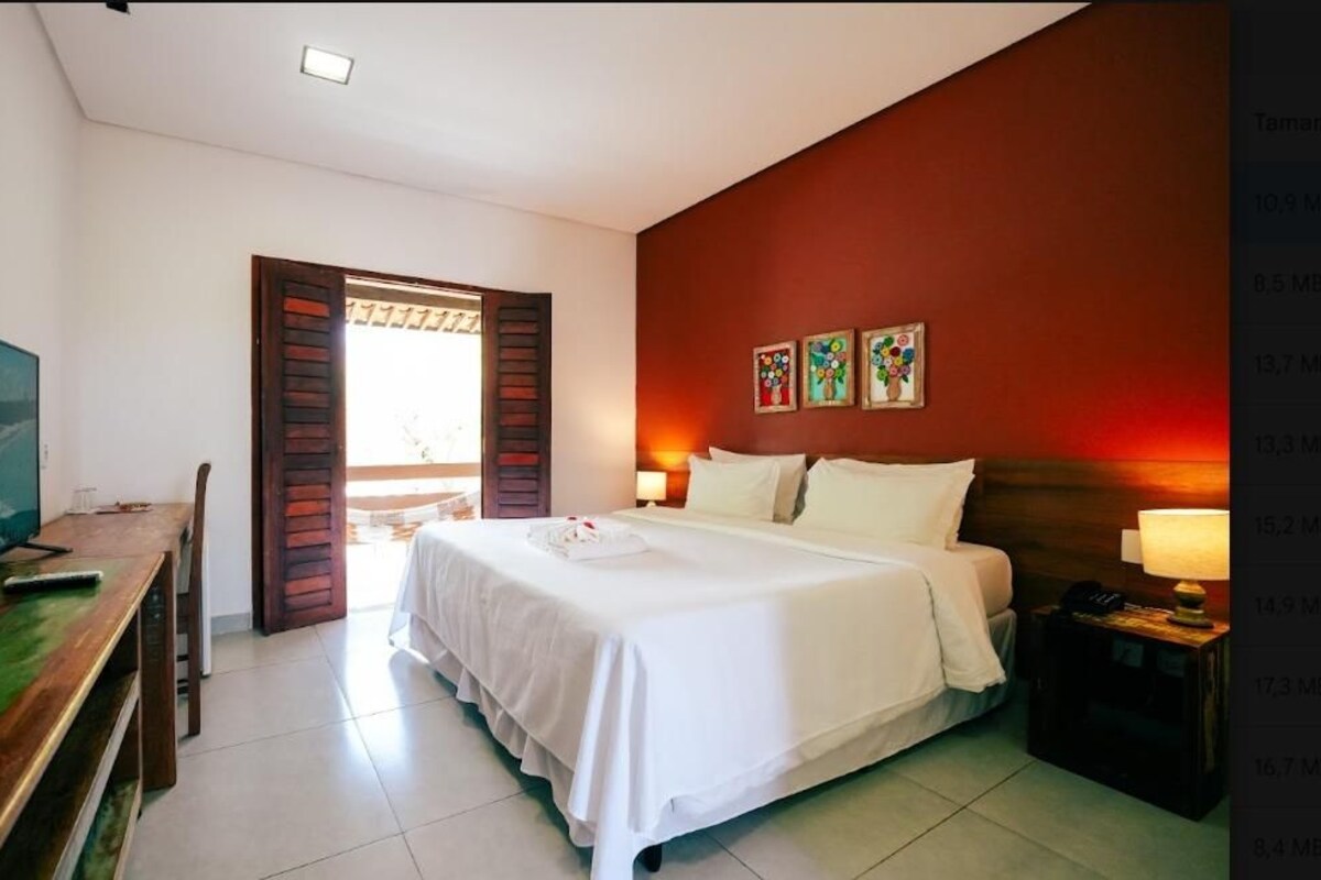 Une chambre d’hôtel comprenant un lit, une table de chevet, une lampe et un bureau avec une chaise.