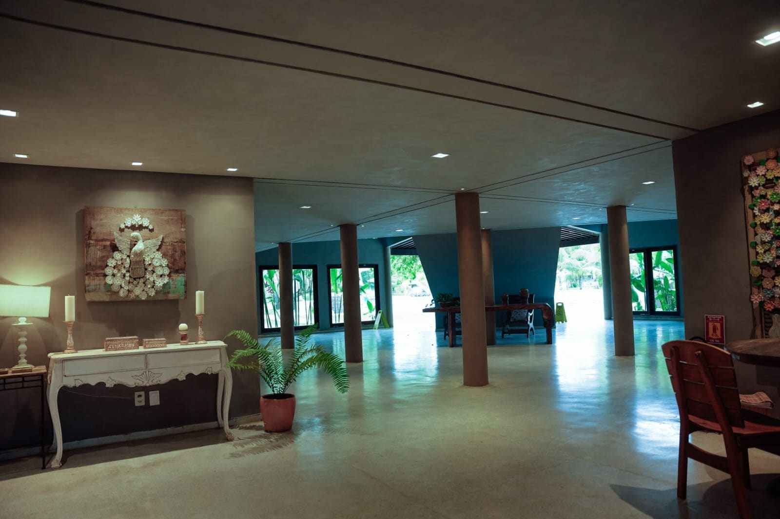 A spacious lobby with a reception desk, a potted plant, and a decorative wall piece.