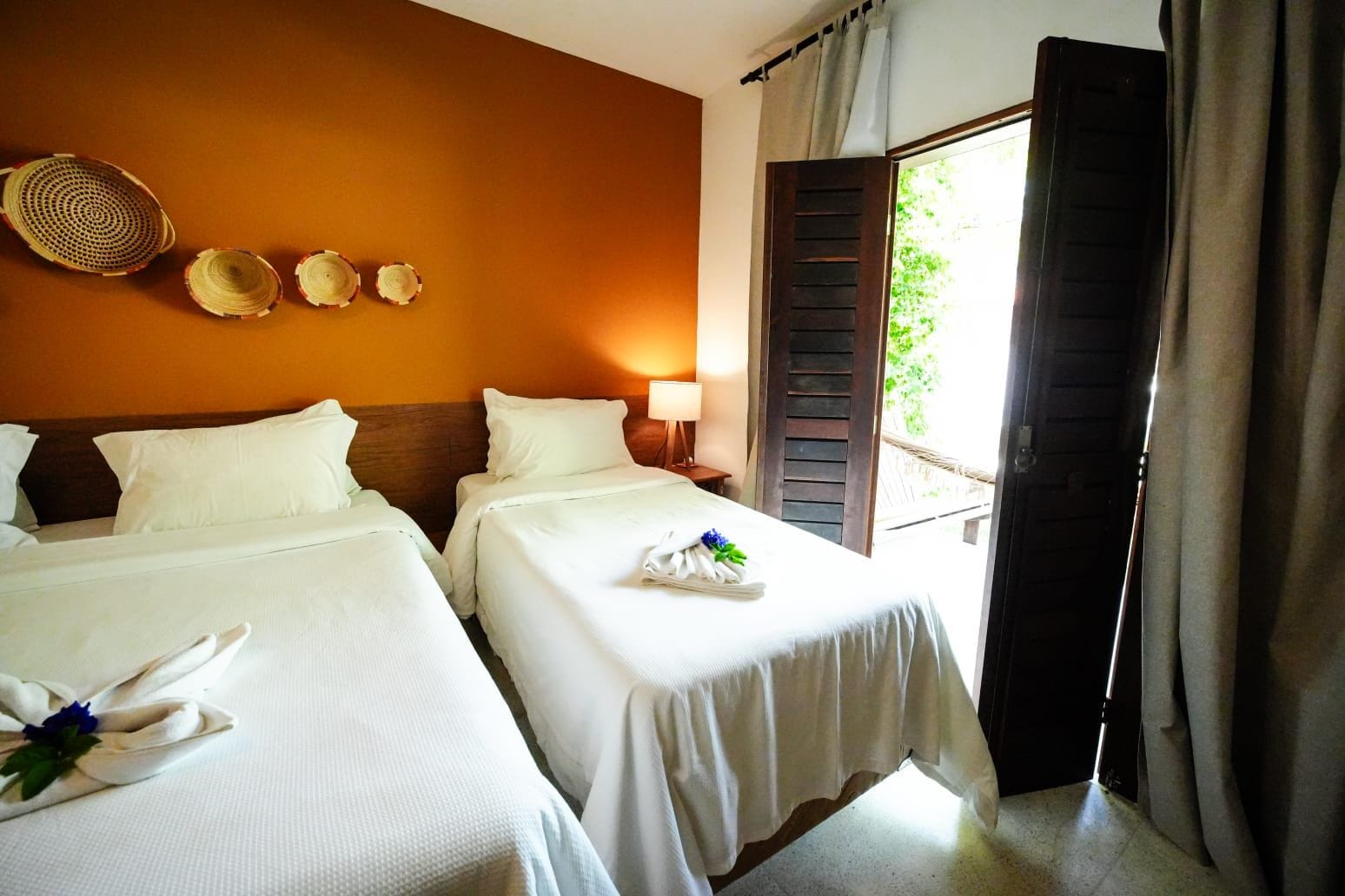 A hotel room with two beds, a window with a view, and a wall with decorative items.