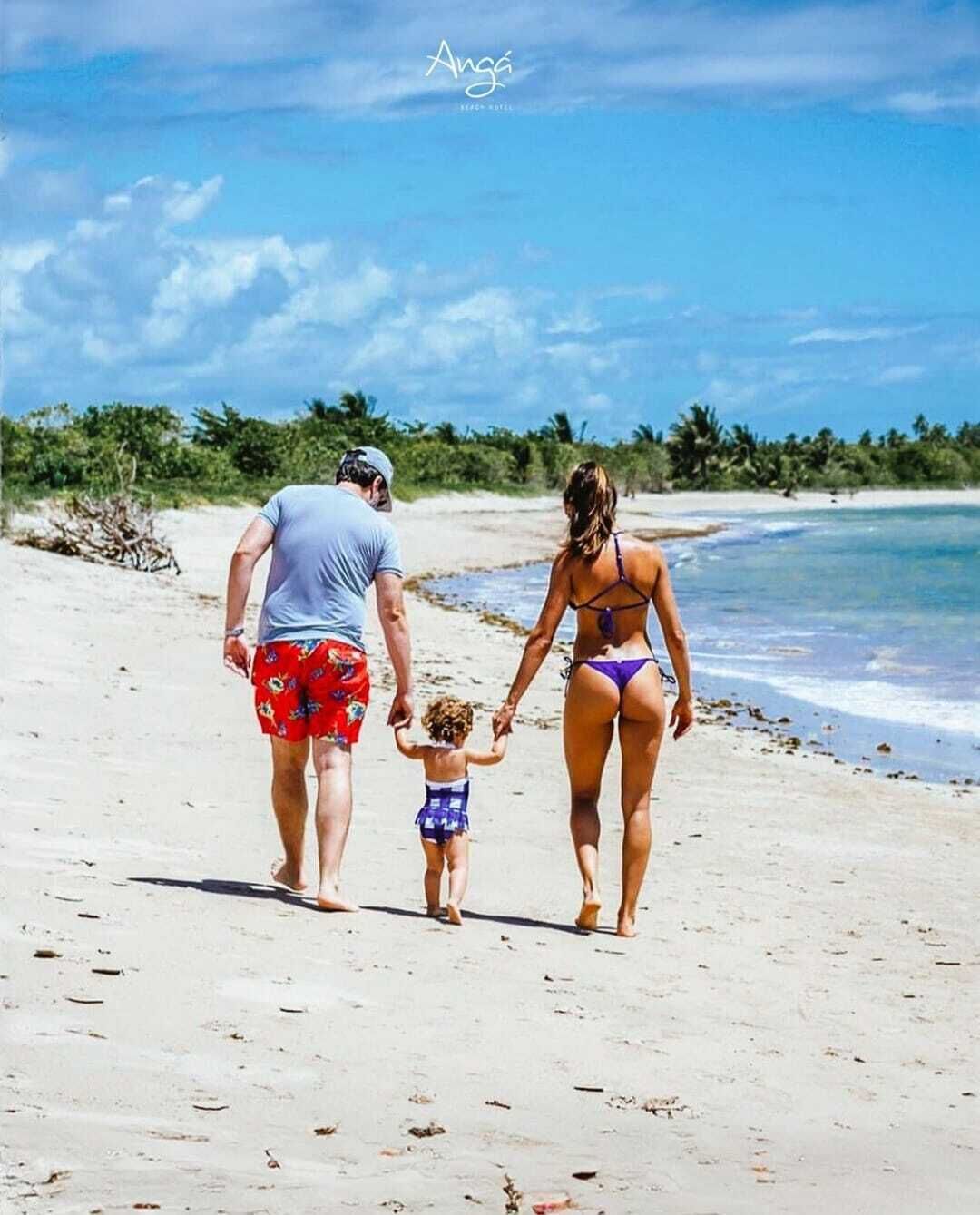 A family walking on a beach with clear skies.