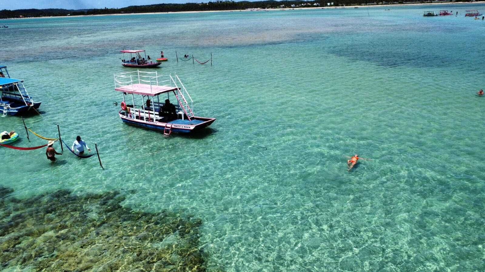 Helder turquoise water met boten en mensen.