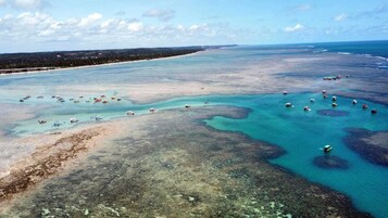 Vista aérea de una zona costera con aguas azul turquesa, playas arenosas y numerosos barcos.