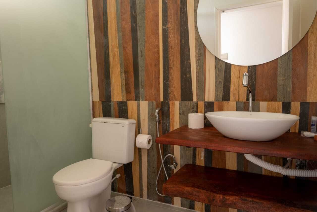 Une salle de bain comprenant des toilettes, un meuble-lavabo en bois avec un évier et un miroir.