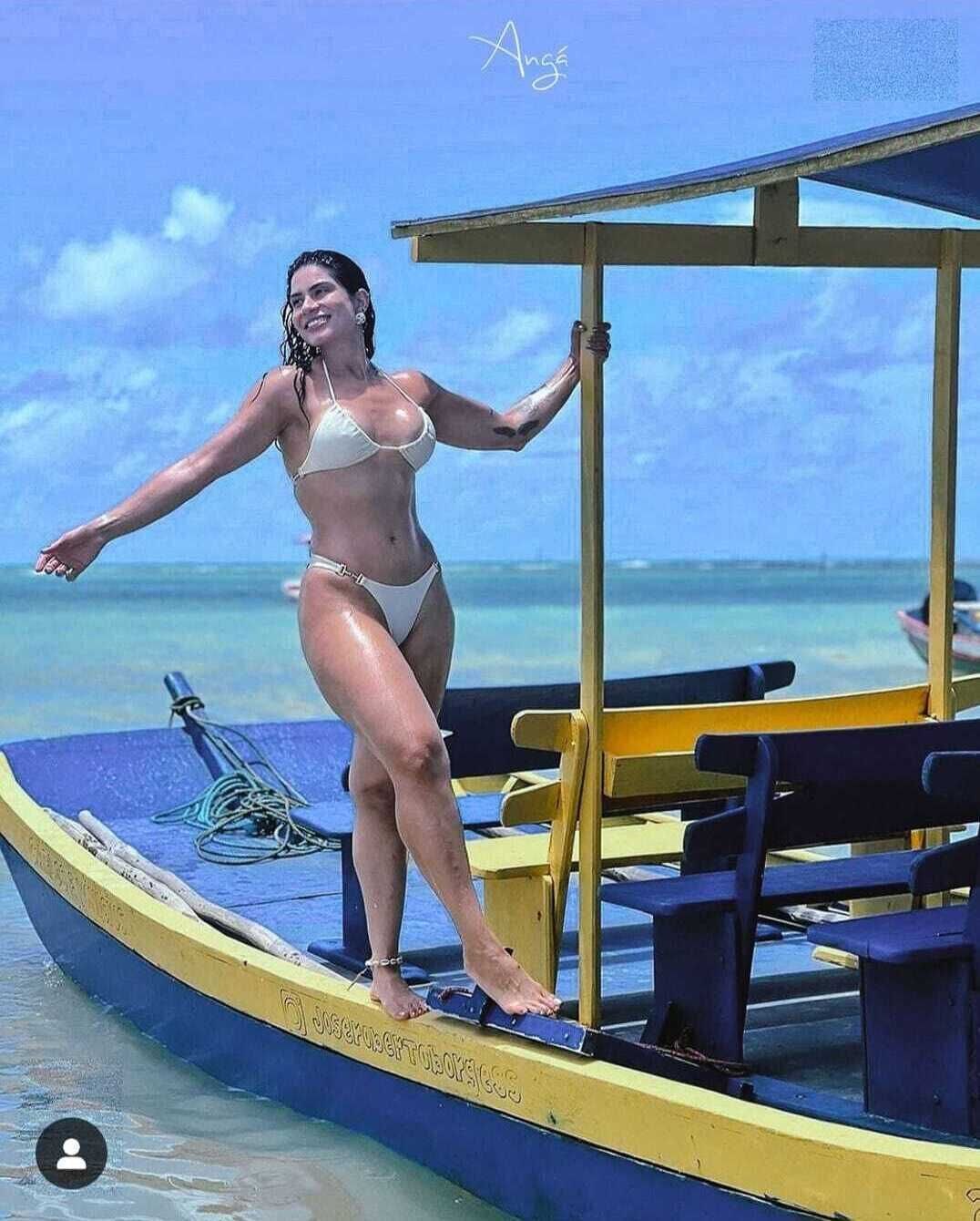 Eine Person steht auf einem Boot und blickt auf das klare Meer und den Himmel.