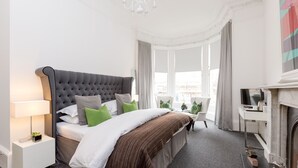 A modern hotel room with a large bed, a desk, a chair, and a fireplace. - 94DR (Edinburgh)