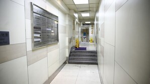 A corridor with tiled walls, a metal staircase, and a sign indicating a fire emergency exit. - Sandhu guest house (Kowloon)
