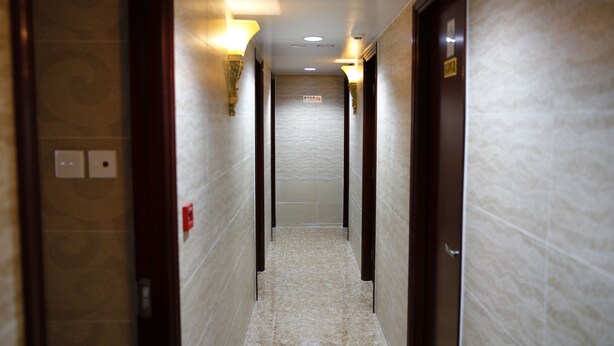 A hallway with a marble floor, wall-mounted light fixtures, and a door at the end. - Sandhu guest house (Kowloon)