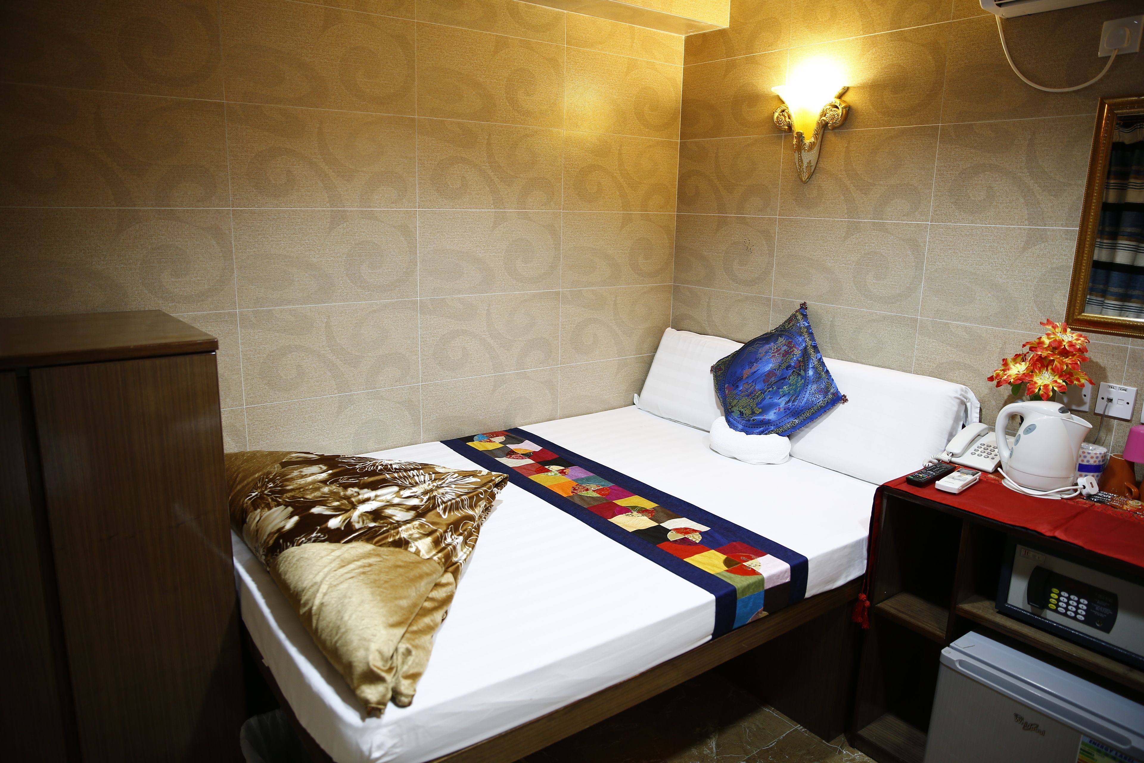 A hotel room with a bed, a nightstand, a microwave, and a wall-mounted light fixture.