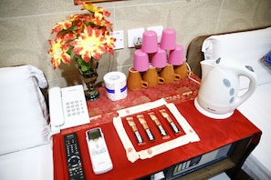 Habitación de hotel con mantel rojo, un florero con flores, un teléfono, un control remoto, un microondas y una tetera.
