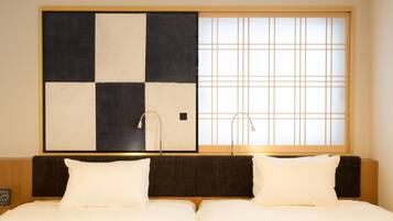 A hotel room with a large bed, a headboard with a dark panel, and a large window with a grid pattern.