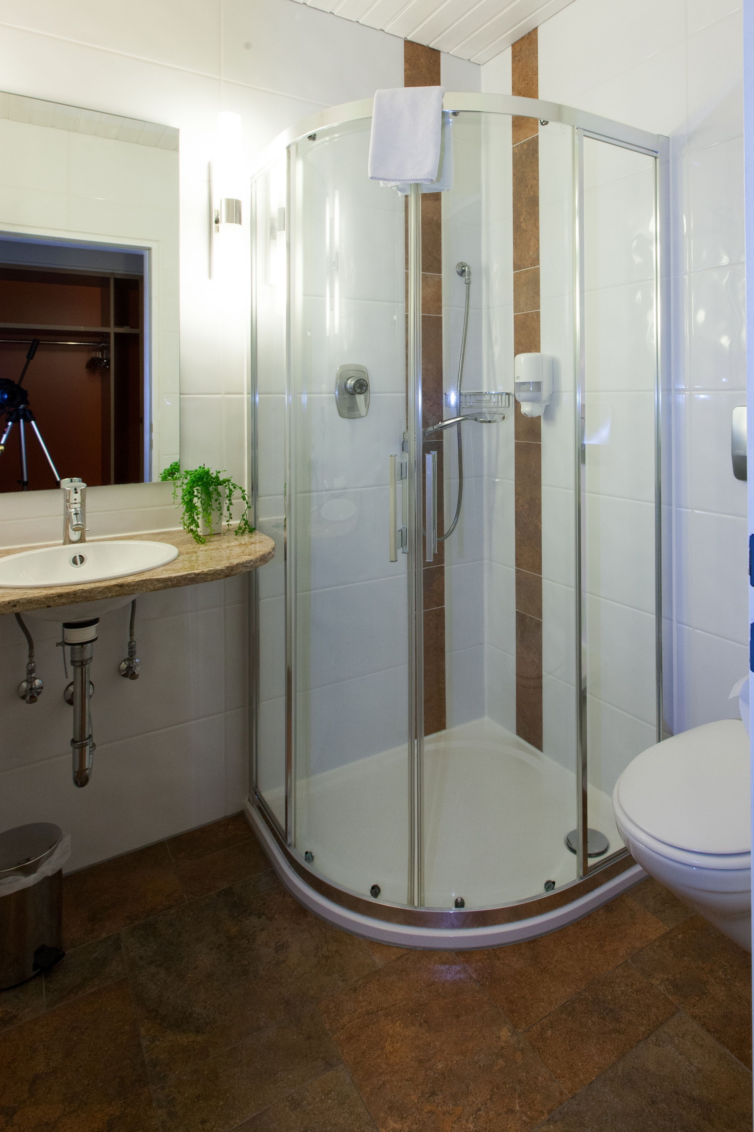 Un baño moderno con ducha acristalada, lavamanos con espejo e inodoro.