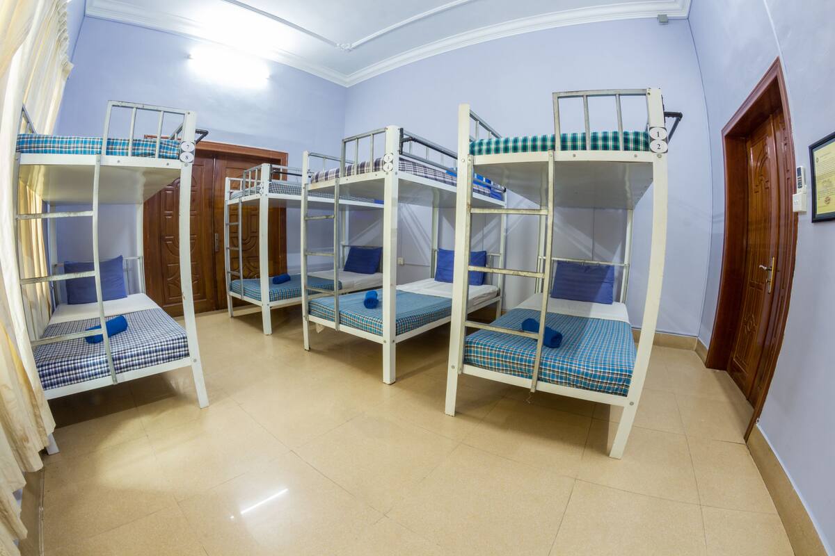 Een kamer met stapelbedden, houten deuren en een betegelde vloer.