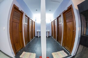 A hallway with wooden doors, a white pillar, and a tiled floor. - Lovely Jubbly Villa - Hostel (Phnom Penh)