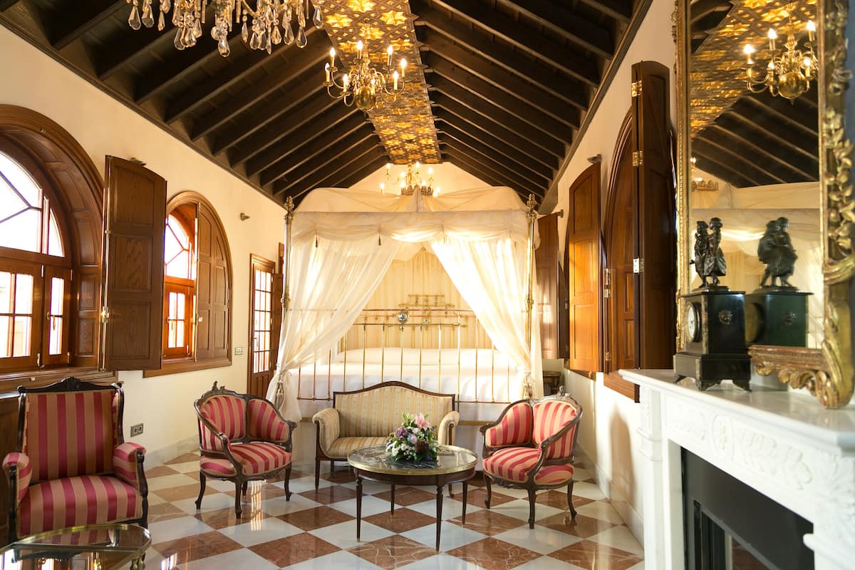 A room with a checkered floor, a canopy bed, and a fireplace.