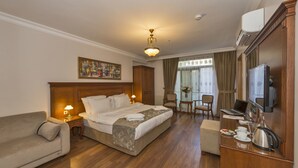 A hotel room with a large bed, a sofa, a desk with a laptop, a television, and a painting on the wall. - Blisstanbul Hotel (Istanbul)