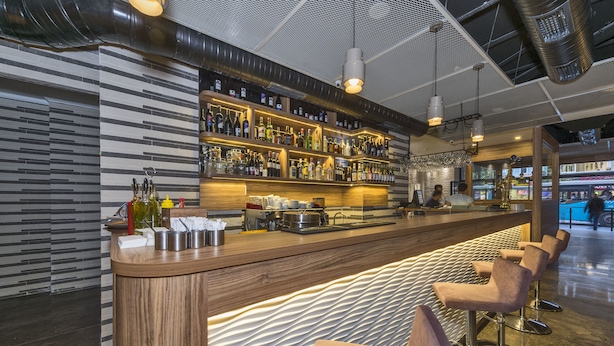 A bar area with a long counter, multiple shelves of bottles, and bar stools. - Blisstanbul Hotel (Istanbul)