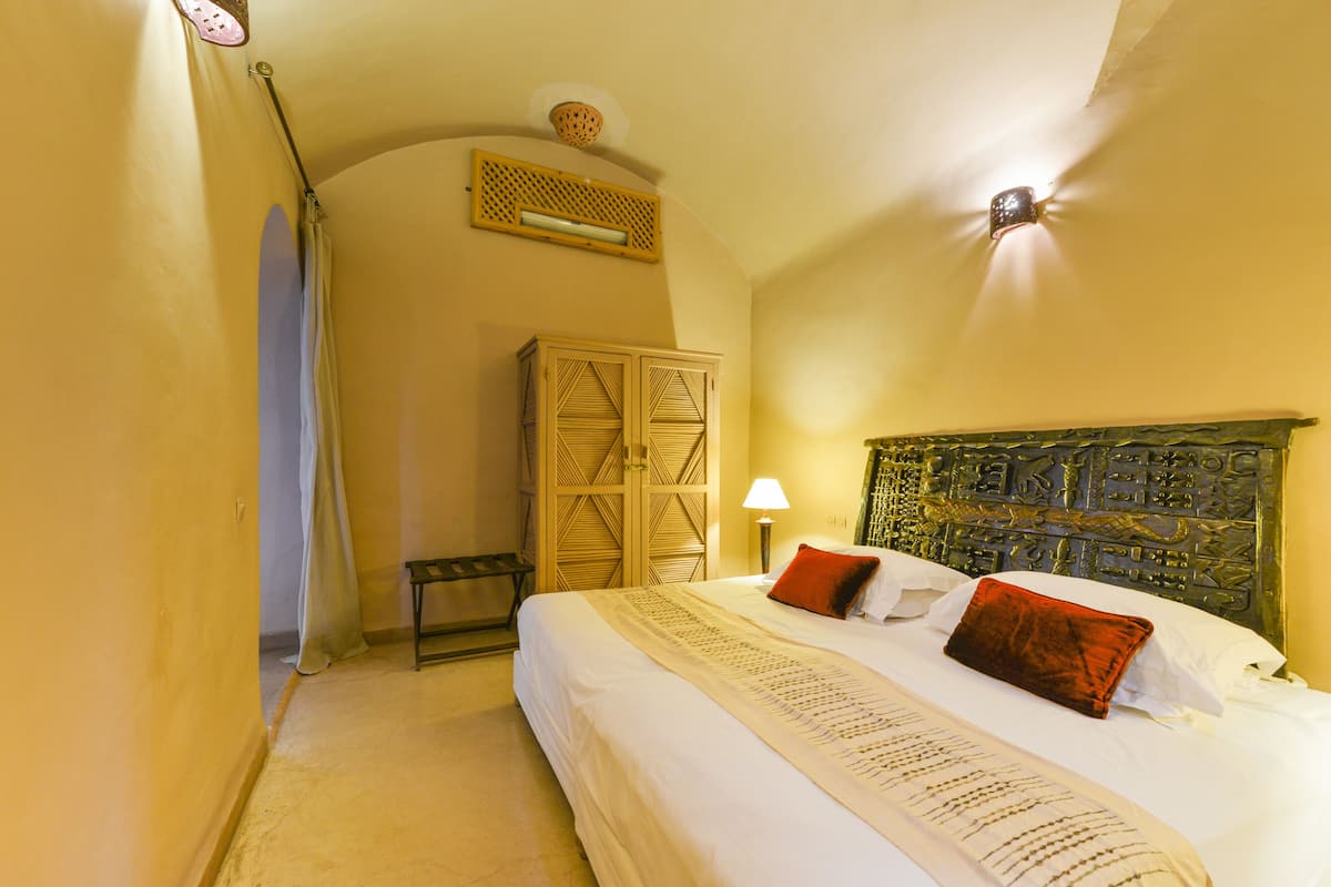 A bedroom with a bed, a nightstand, a lamp, and a wardrobe.