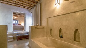 A spacious bathroom with a large bathtub, a wooden ceiling, and a small alcove with a decorative item. - Hôtel Riad Caravan Serai (Marrakech)