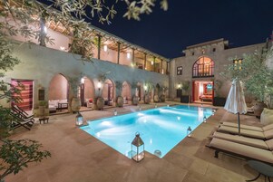 Una piscina al aire libre, sombrillas, sillones reclinables de piscina