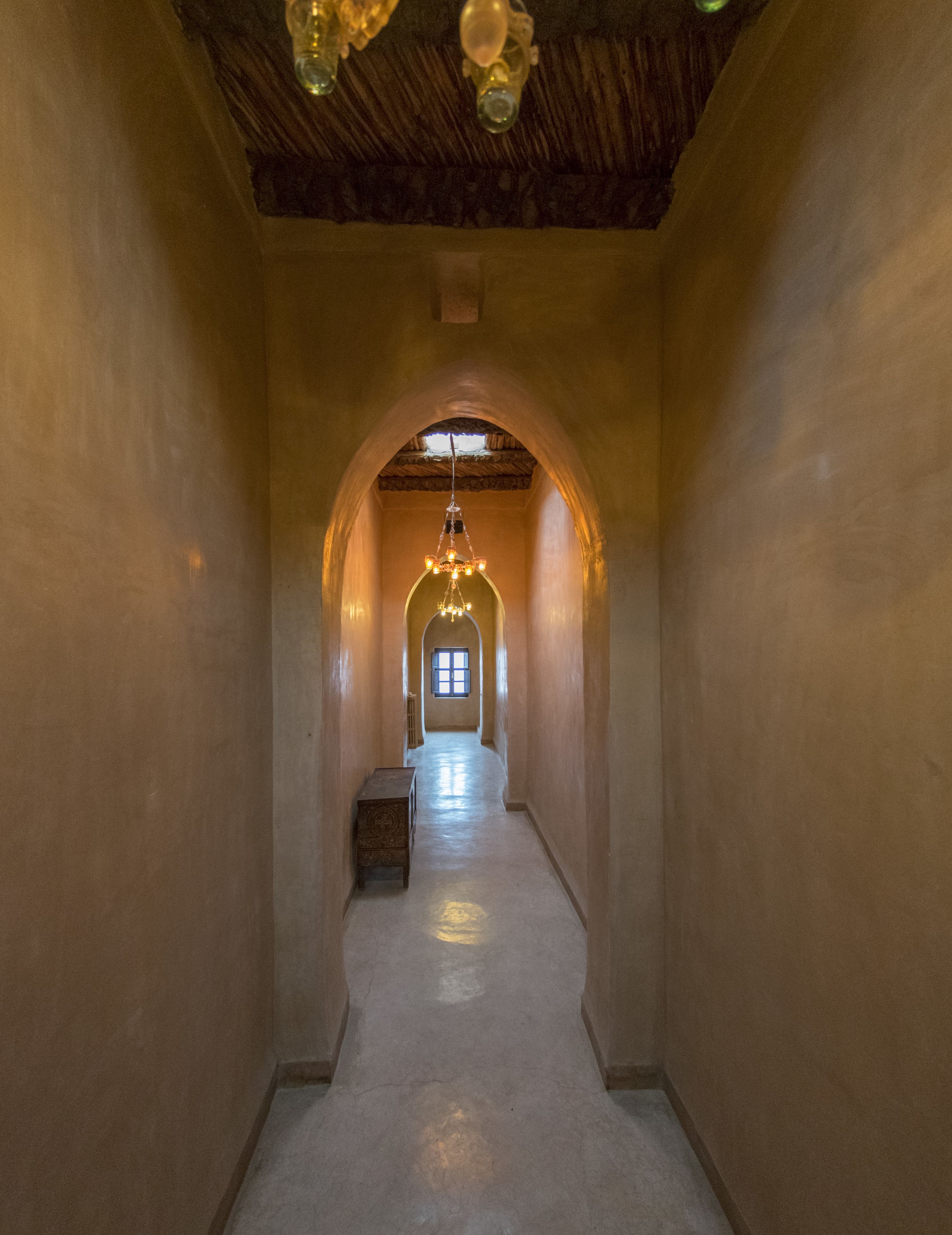 A hallway with an arched ceiling, a chandelier, and a small table.
