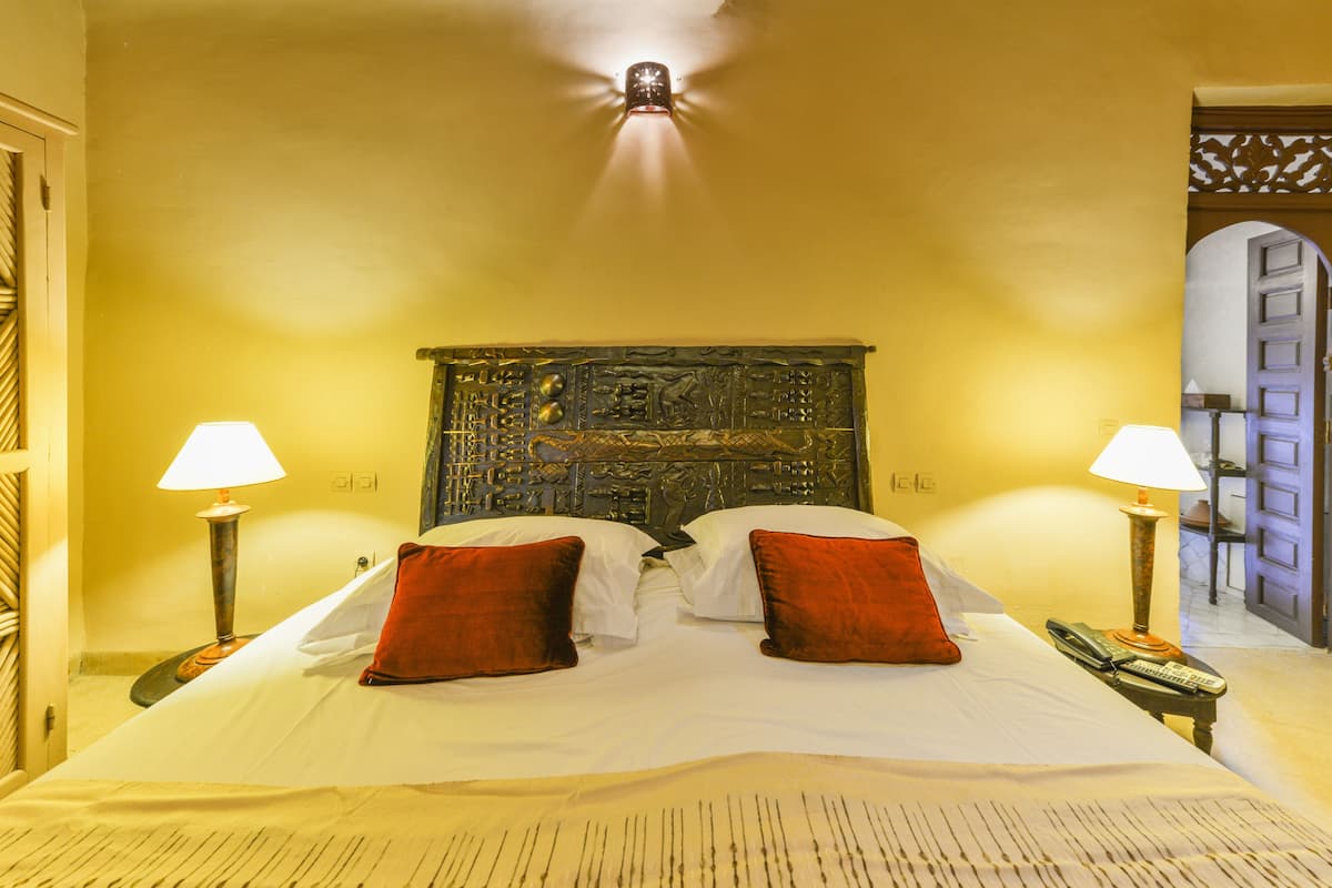 A hotel room with a large bed, two bedside lamps, and a decorative headboard.