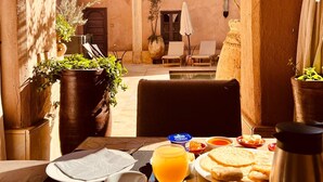 A table set for breakfast with plates of food, a coffee cup, and a glass of orange juice. - Hôtel Riad Caravan Serai (Marrakech)