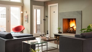 A modern living room with a fireplace, comfortable seating, and a glass coffee table. - 8 Dyer Hotel (Provincetown)