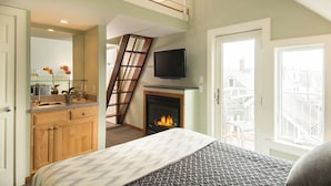 A bedroom with a lofted sleeping area, a fireplace, a television, and a view of the city. - 8 Dyer Hotel (Provincetown)