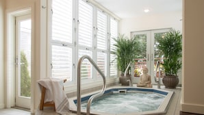 A spa area with a hot tub, large windows, and potted plants. - 8 Dyer Hotel (Provincetown)