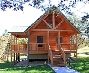 A wooden cabin with a porch, a staircase, and a door. - Acorns Resort (Milford)