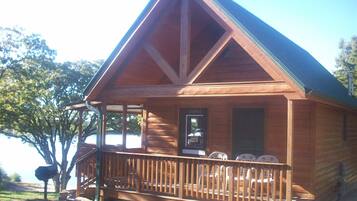 A wooden cabin with a porch, a sign indicating "Cabin 5", and a view of the surrounding area.