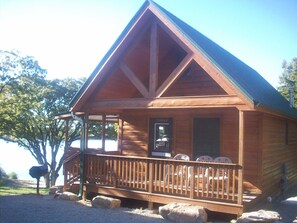 A wooden cabin with a porch, a sign indicating "Cabin 5", and a view of the surrounding area.