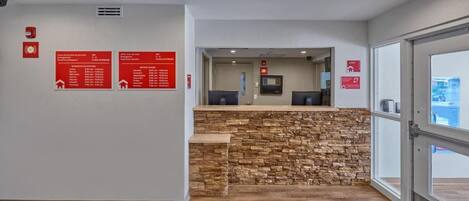 A reception area with a stone counter, a fire alarm, and informational signs on the wall.