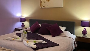 A hotel room with a large bed, two nightstands, a bench, and a wall-mounted artwork.