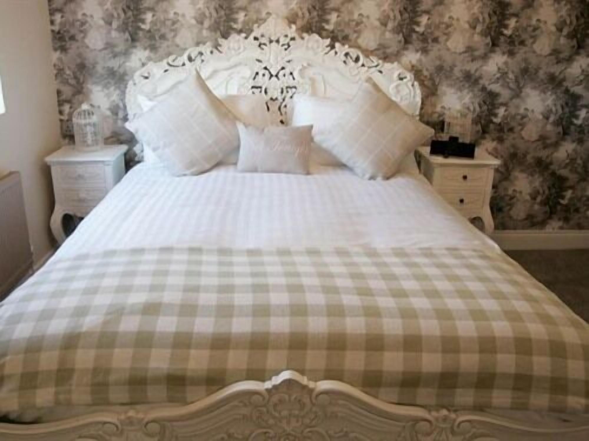 A bed with a checkered bedspread and a decorative headboard.
