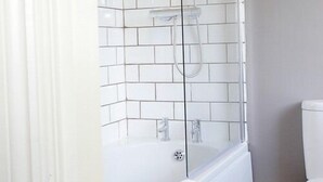 A modern bathroom with white tiles, a glass-enclosed shower, and a white toilet. - The Lambton Worm (Chester-le-Street)