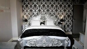 A bedroom with a large ornate bed, a patterned wallpaper, and a chandelier. - The Lambton Worm (Chester-le-Street)