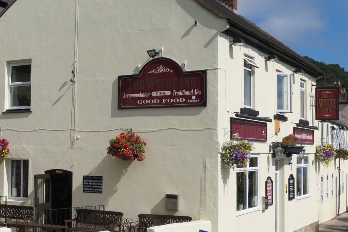 A traditional pub with a sign advertising accommodation, pool, and good food.