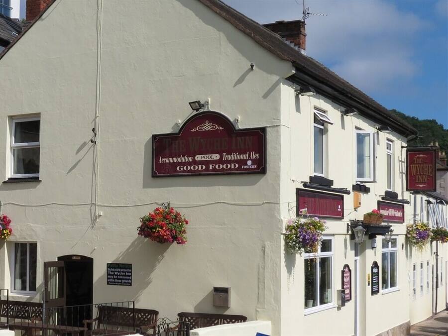 A traditional pub with a signboard advertising accommodation, pool, and good food.