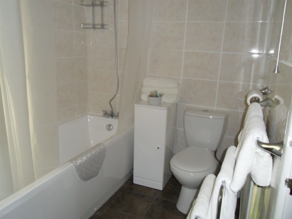 A bathroom with a bathtub, toilet, and a shower area.
