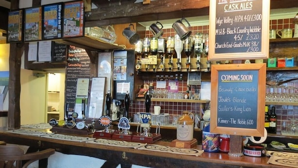 A bar area with a sign indicating cask ales and a menu board listing prices. - The Wyche Inn (Malvern)