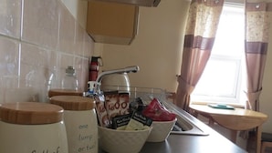 A kitchen counter with two white containers labeled 'full of beans' and 'one lump or two?' holding coffee pods and a small bag. - The Wyche Inn (Malvern)