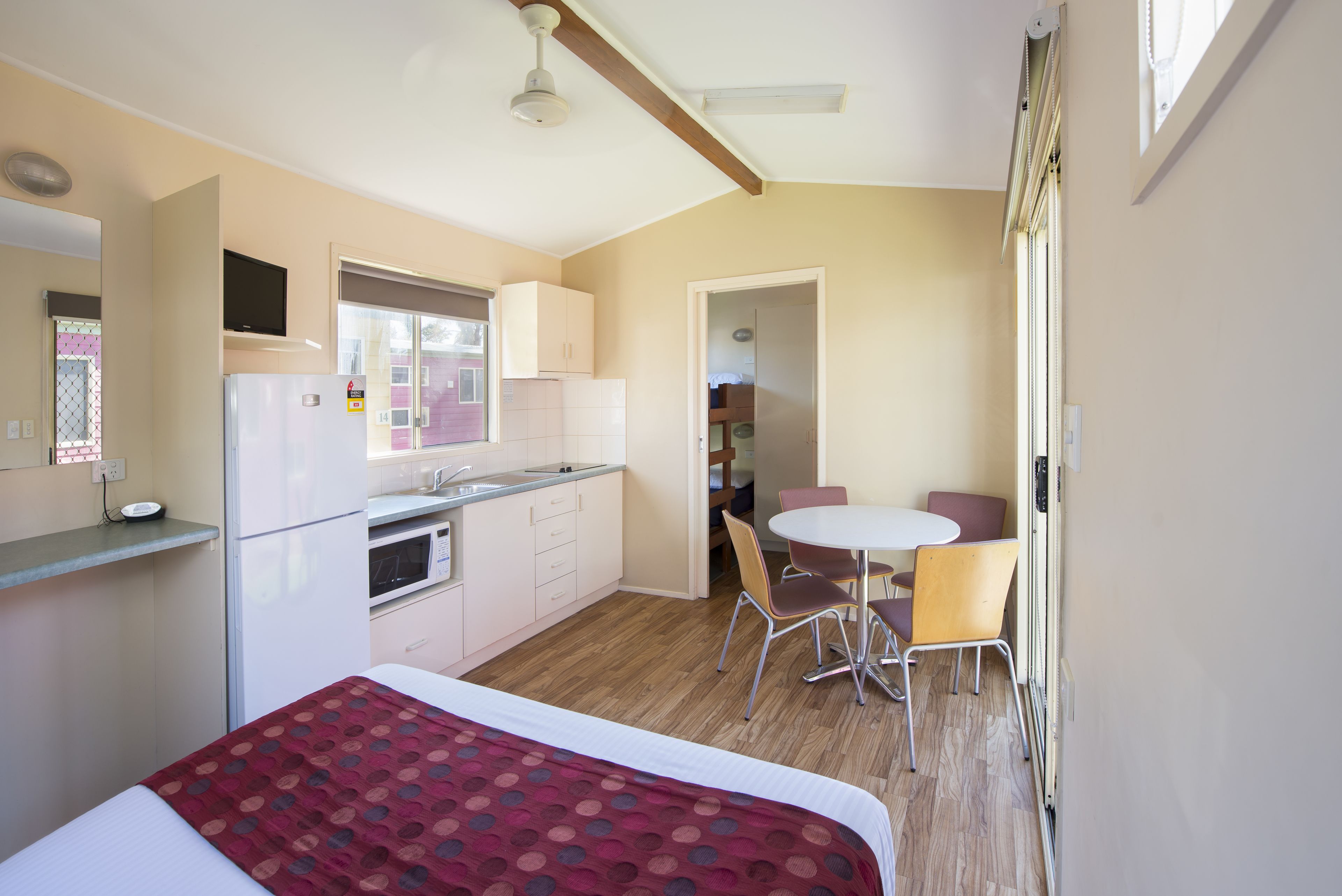 Una habitación compacta con cama, kitchenette, comedor y baño.