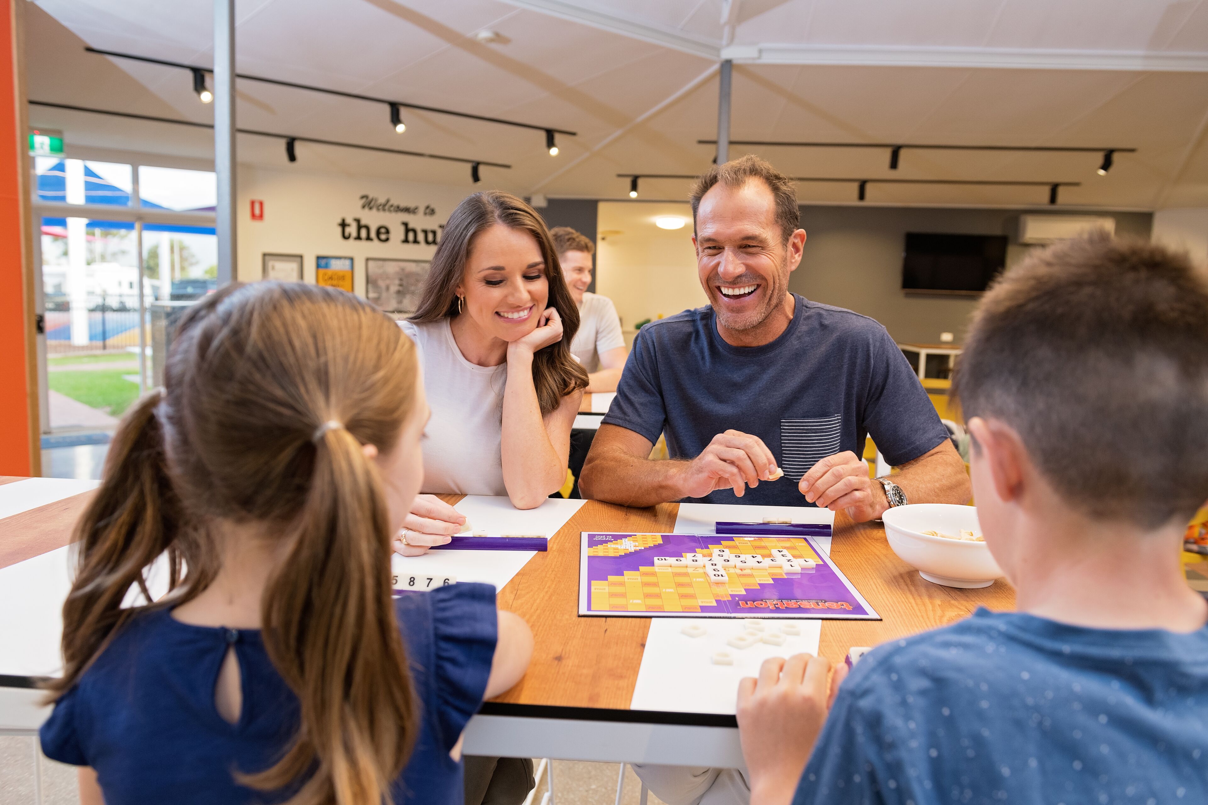 A group of people playing a board game at a table in a well-lit indoor space with a modern design.